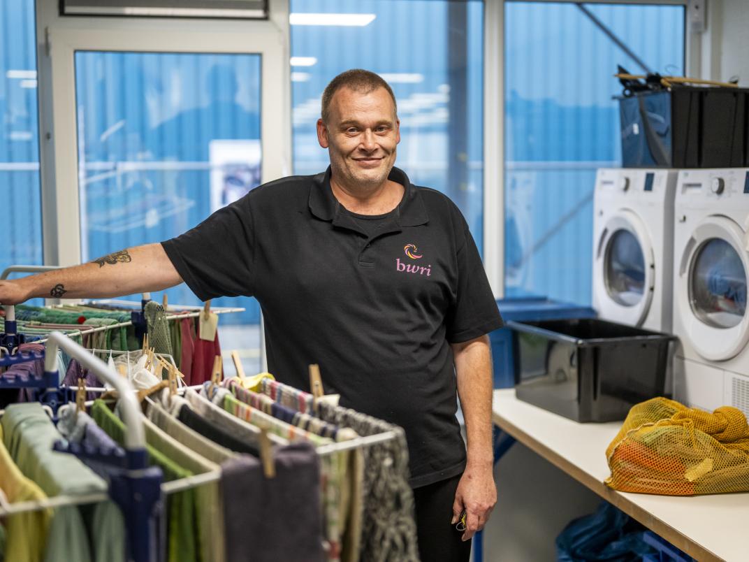 Man bij wasmachine en droogrek. 