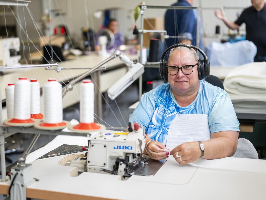 Persoon werkt achter een naaimachine.