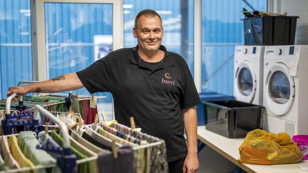 Man bij wasmachine en droogrek. 