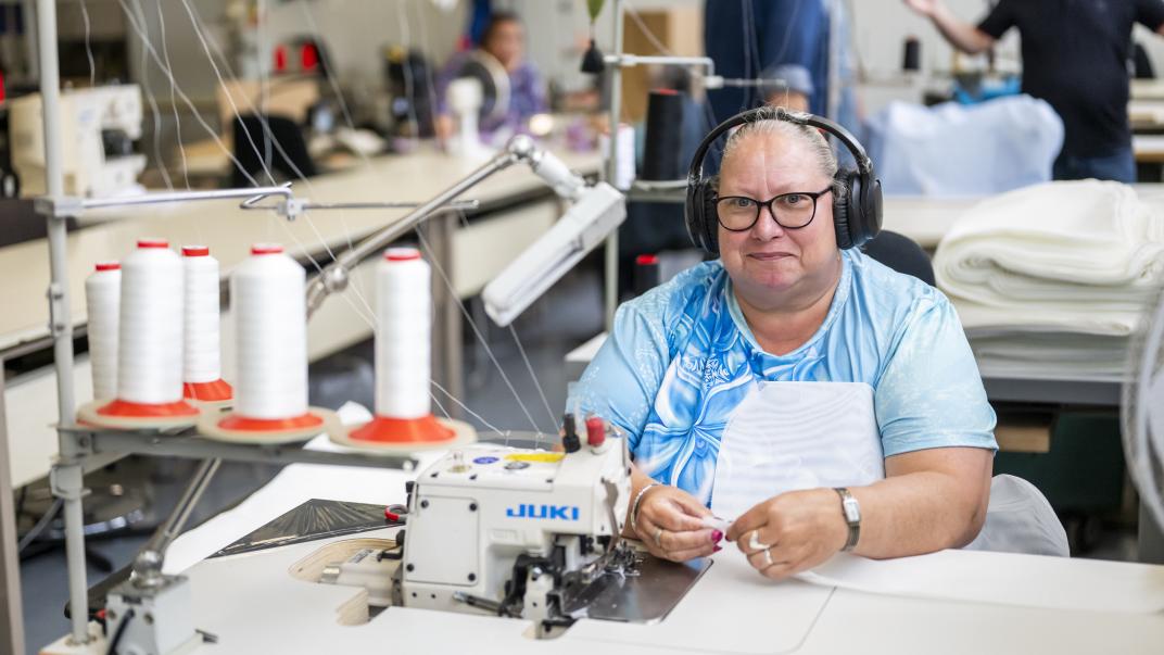 Persoon werkt achter een naaimachine.